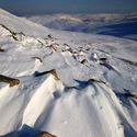 Sculpted snow and ice, Swirral Edge, Helvellyn with High Street glowing in the distance, Lake District