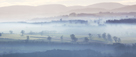 Mist, trees and fields south west of Penrith with Lake District fells beyond