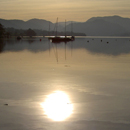 Sun and boats reflected in Ullswater on beautiful calm Autumn evening