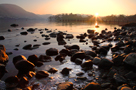 Sunset over Ullswater in Winter with rocks and ice in foreground, near marina, Watermillock, Lake District