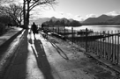 Black and white image of a woman walking her dog beside Derwentwater near Keswick Boat Landings with Catbells in background