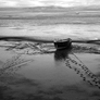 Footprints in mud leading to and from Fishing boat at low tide in Morecambe Bay. Southern Lake District seen in distance