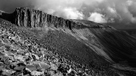Black and white image of the imposing rocks of High Cup Scar forming south east side part of High Cup Nick, beneath a dramatic sky, Pennines