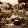 Morland Beck in Spring with Cherry blossom on tree and Mill Yard Cafe beside bridge in background