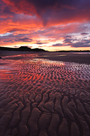 Fiery sunset relected in wet sands sands of Embleton Bay